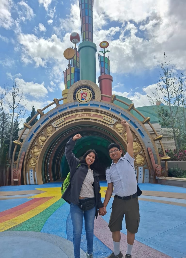 Couple posing in front of a colorful steampunk-themed rocket arch at a theme park